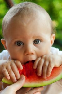 Un bebeluș practicând pe un pepene diversificarea de la 6 la 9 luni